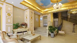 Un hall d’entrée luxueux, agrémenté de meubles richement décorés, d’un magnifique escalier et d’un lustre.