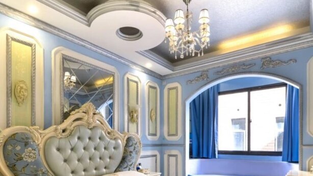Une chambre à coucher avec un grand lit, une tête de lit décorée et un lustre.