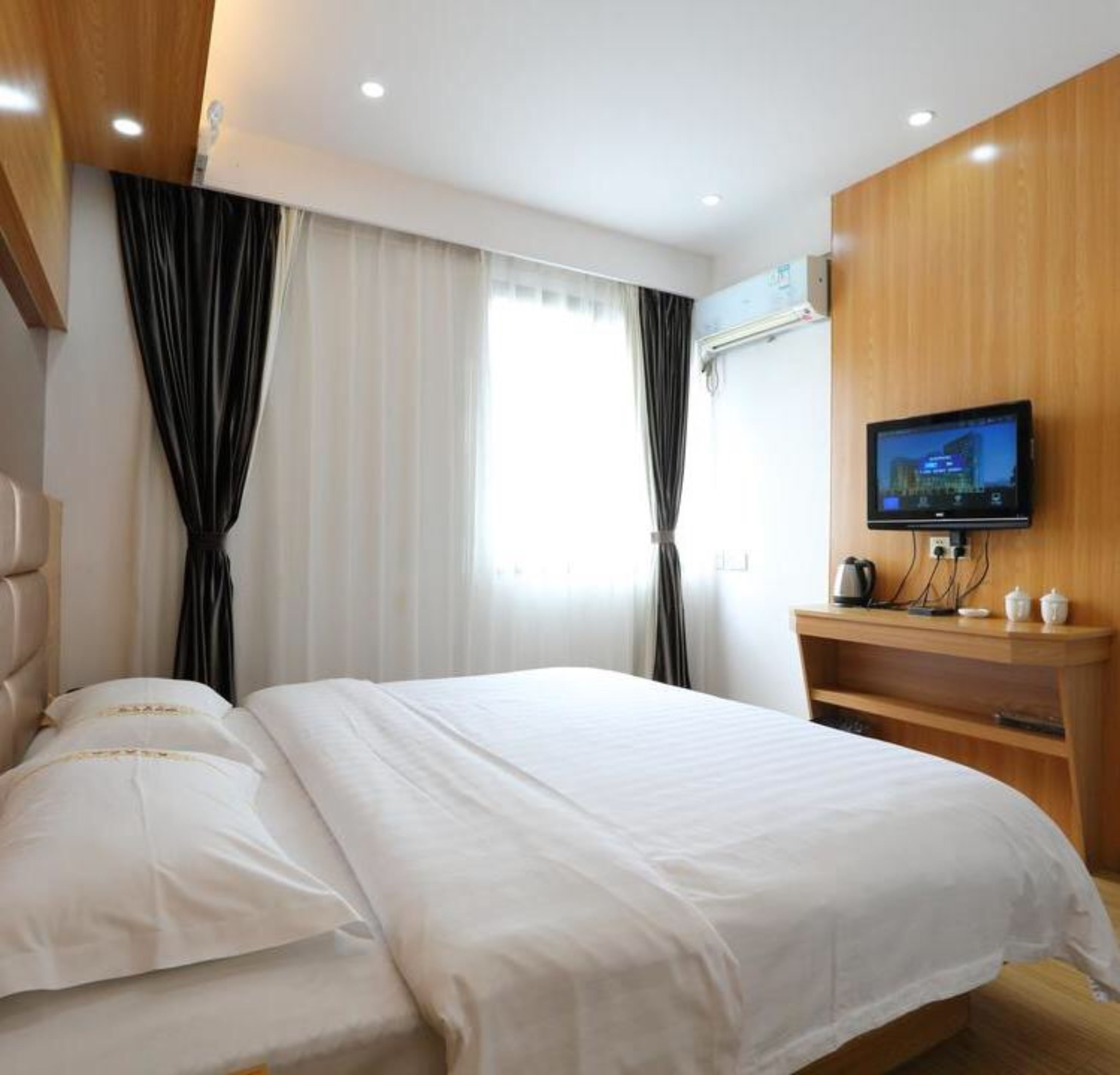 Ein Hotelzimmer mit Bett, Fernseher und einer Wand aus Holzverkleidung.
