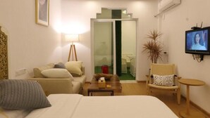 Une chambre d’hôtel équipée d’un lit, d’un bureau, d’une chaise, d’une télévision et d’une porte-fenêtre coulissante donnant sur un balcon.