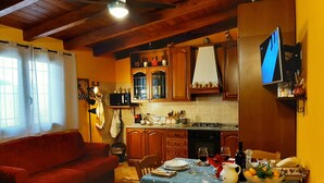 Une cuisine chaleureuse avec des meubles en bois, une table à manger dressée avec des assiettes et des verres, et un canapé rouge dans le salon.
