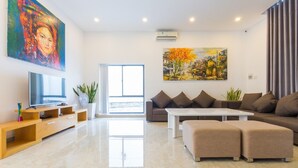 A modern living room with a flat-screen TV, a large painting, a sofa, and a coffee table. - Villa Royal 2 (Ho Chi Minh City)