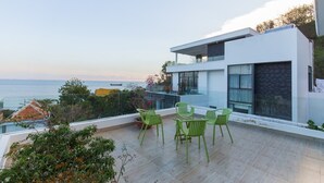 A modern two-story building with a balcony featuring green chairs and a view of the sea. - Villa Royal 2 (Ho Chi Minh City)