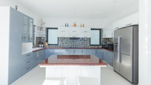 A modern kitchen with a central island, white cabinets, and stainless steel appliances. - Villa Royal 2 (Ho Chi Minh City)