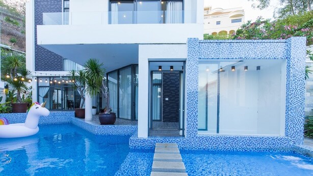 A modern house with a swimming pool, a unicorn float, and potted plants. - Villa Royal 2 (Ho Chi Minh City)