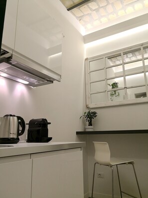 A modern kitchen with a built-in stove, a coffee maker, and a window with a view of the outside. - Luxury Rooms near Colosseum (Rome)
