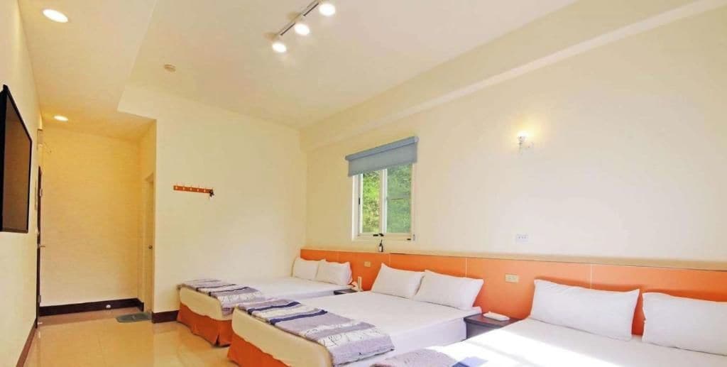 Quarto de hotel com duas camas, uma janela e uma porta.