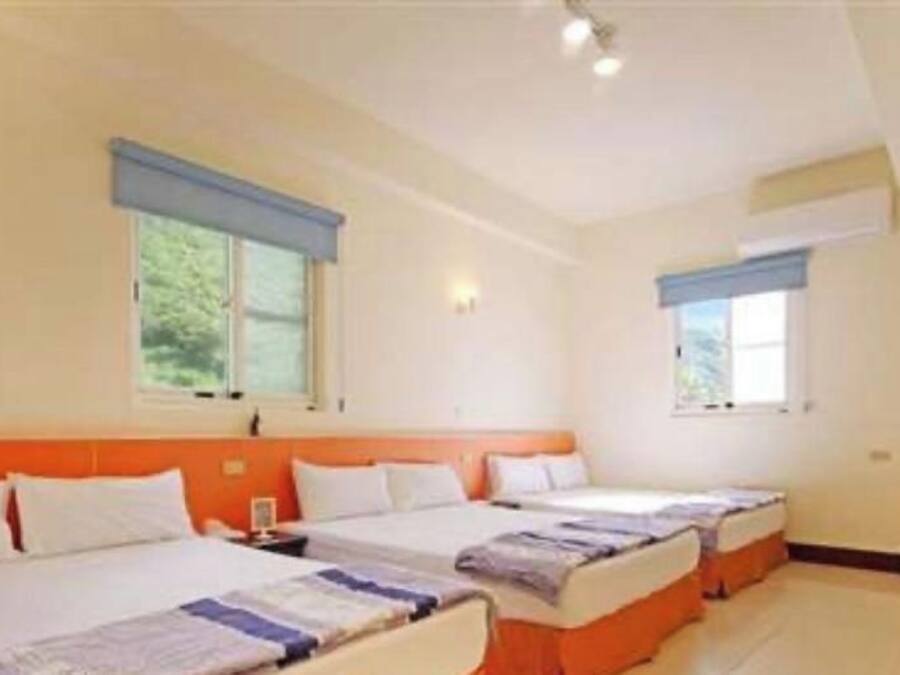 Une chambre d’hôtel avec deux lits, une chaise et un téléviseur fixé au mur.