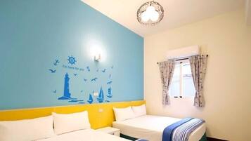A hotel room with a bed, a window with curtains, a wall with nautical-themed decals, and a ceiling light fixture.