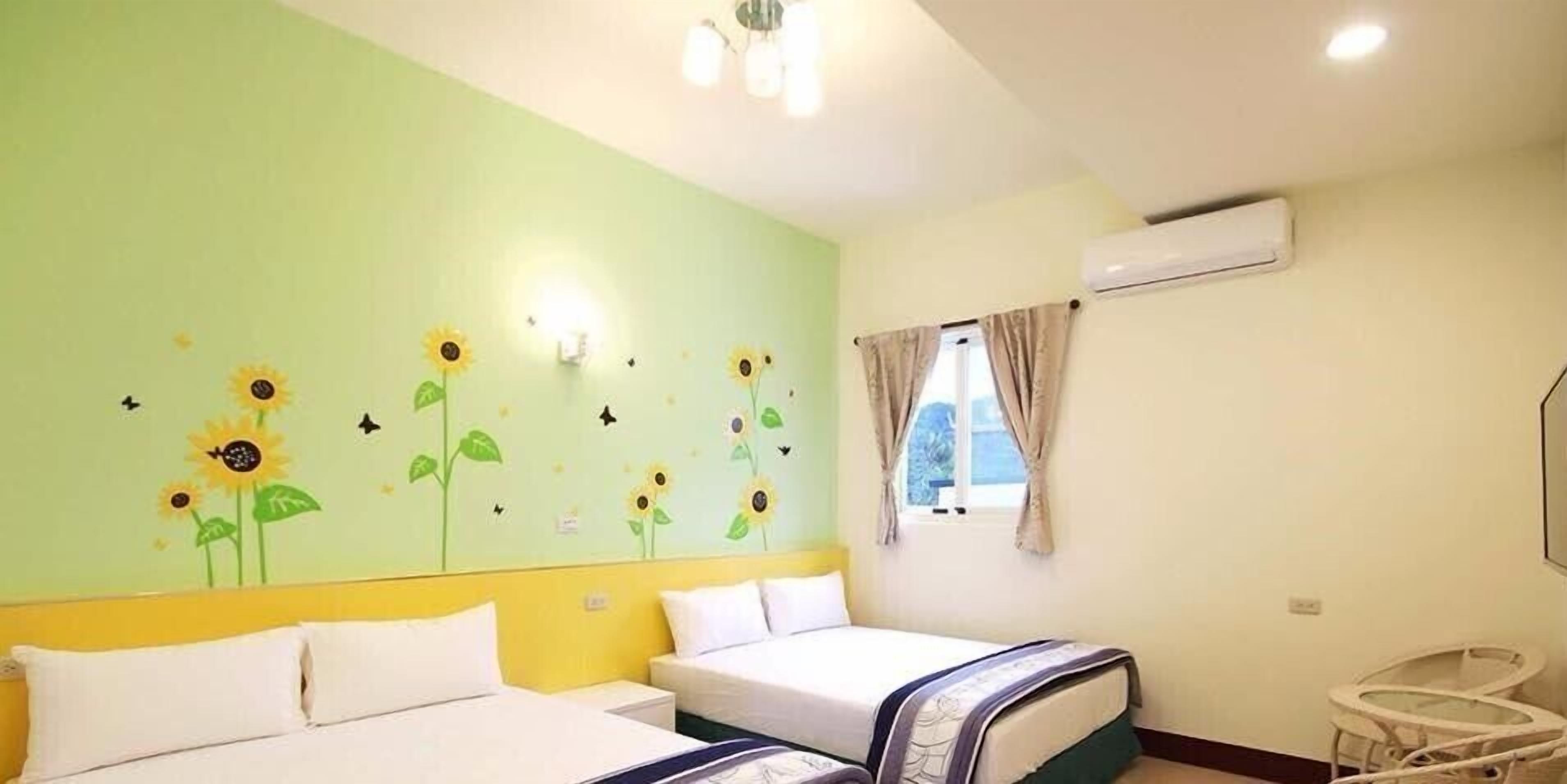 A room with two beds, a window with curtains, and a wall-mounted air conditioner.