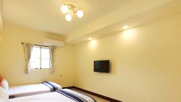 Habitación de hotel con cama, televisor de pantalla plana en la pared y ventana con cortinas.