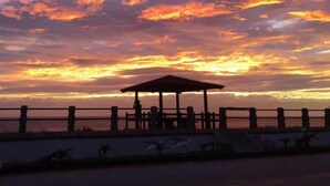 Ein Sonnenuntergang mit einem hölzernen Gazebo und einer Umzäunung am Ufer.