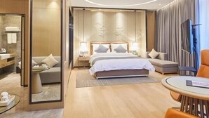 A modern hotel room with a large bed, a sitting area with a round table, and a TV. - Sibeisi International Hotel (Quanzhou)