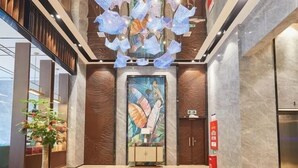 A modern lobby with a large abstract painting, a potted plant, and a fire extinguisher. - Sibeisi International Hotel (Quanzhou)