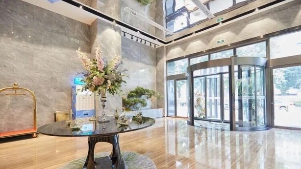 A lobby with a glass table, a reception desk, and a large glass door leading outside. - Sibeisi International Hotel (Quanzhou)