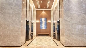 A modern elevator with marble walls and a geometric patterned carpet. - Sibeisi International Hotel (Quanzhou)