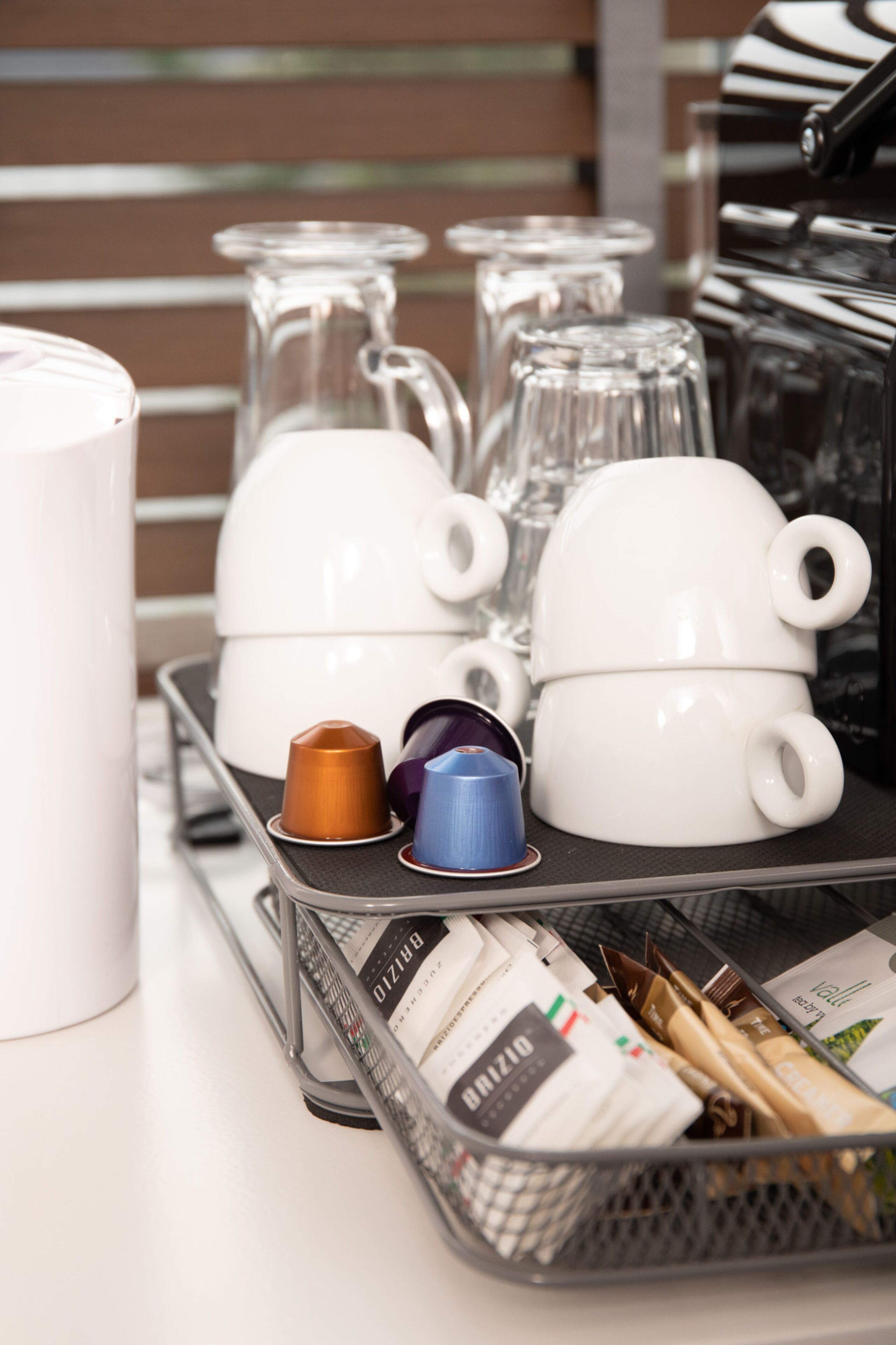 A tray with coffee cups, a coffee pot, and a basket of coffee packets.