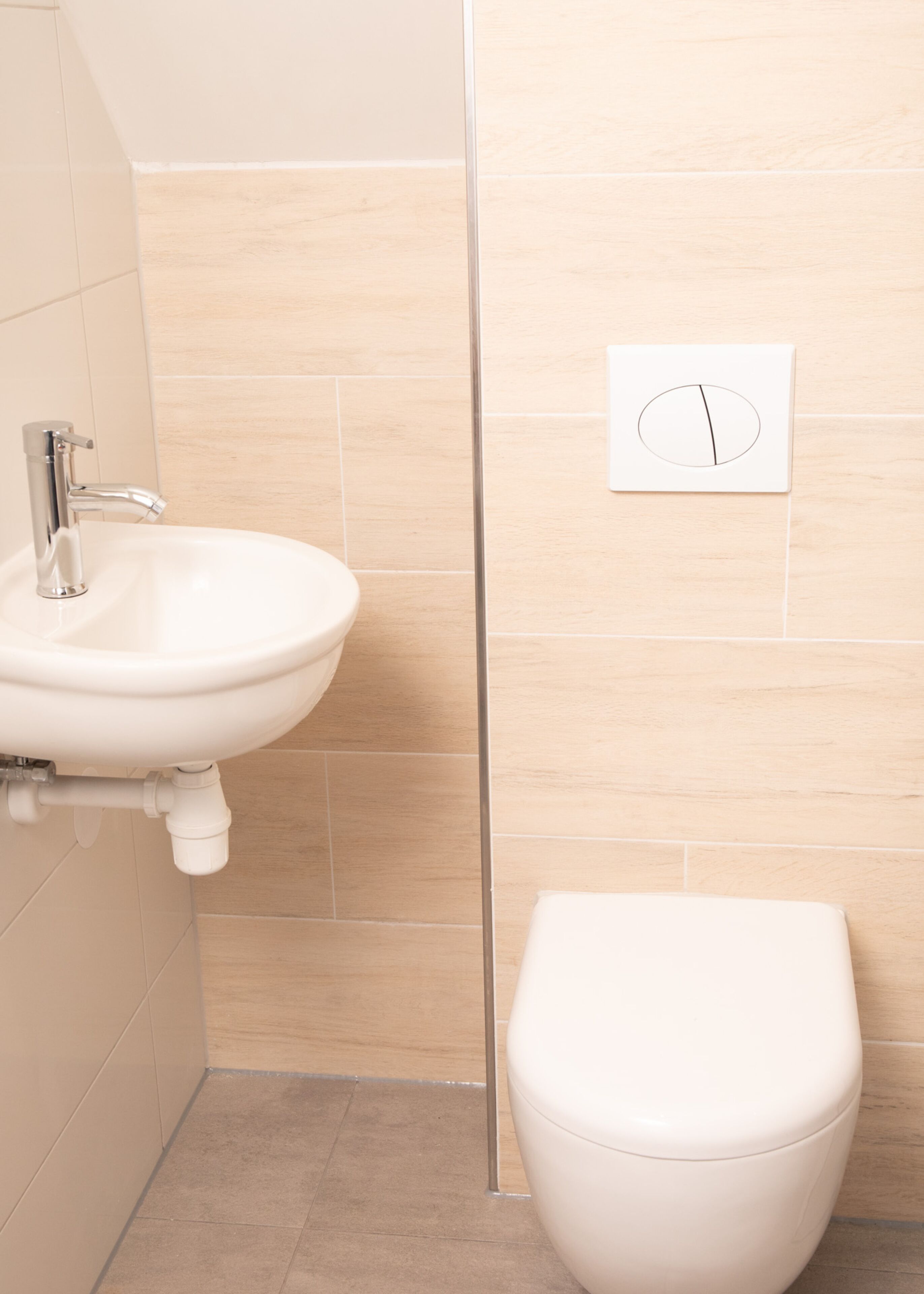 A bathroom with a sink, toilet, and a wall-mounted light switch.