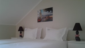 Una camera d'albergo con un letto, due comodini, due lampade e un quadro appeso al muro.