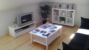 Un soggiorno con televisione, un tavolino da caffè con riviste, una libreria e un lucernario.