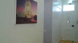 Un corridoio con un quadro raffigurante un castello, una porta bianca e un interruttore a muro.