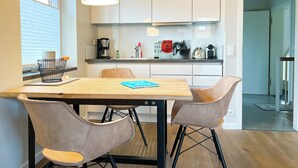 Une cuisine moderne avec des meubles blancs, une table à manger en bois et deux chaises.