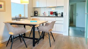 Une cuisine moderne avec des meubles blancs, une table à manger en bois et quatre chaises.