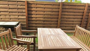 Un espace extérieur aménagé avec des meubles en bois, comprenant une table et quatre chaises.