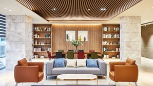 A modern lobby with a wooden ceiling, two sofas, a coffee table, and a bookshelf with books and a vase of flowers. - Lavi de Atlan Hotel (Busan)