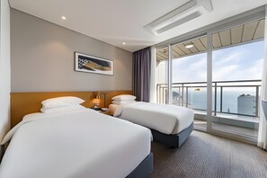 A hotel room with two beds, a large window with a view, a painting on the wall, and a ceiling light. - Lavi de Atlan Hotel (Busan)