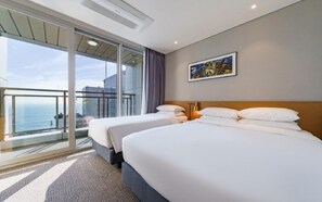 Una habitació d'hotel amb dos llits, un balcó amb vista al mar i un quadre a la paret.