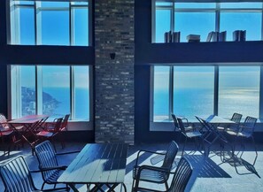 A spacious room with large windows offering ocean views, a brick wall, and multiple seating areas with tables and chairs. - Lavi de Atlan Hotel (Busan)