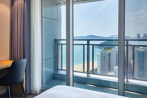 A hotel room with a large window offering a view of the beach and cityscape. - Lavi de Atlan Hotel (Busan)