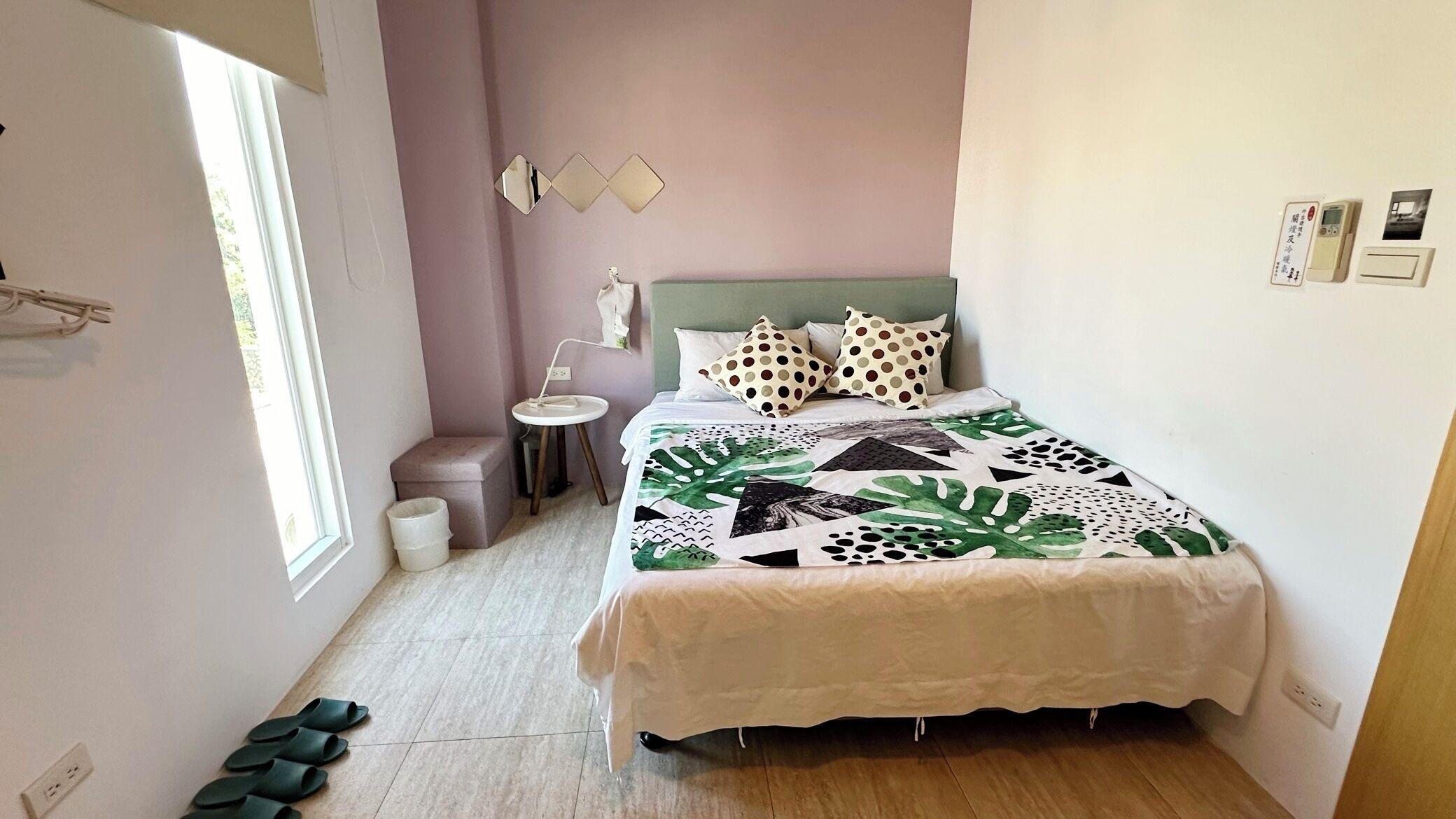 Un dormitorio con cama, mesita de noche y un taburete pequeño.