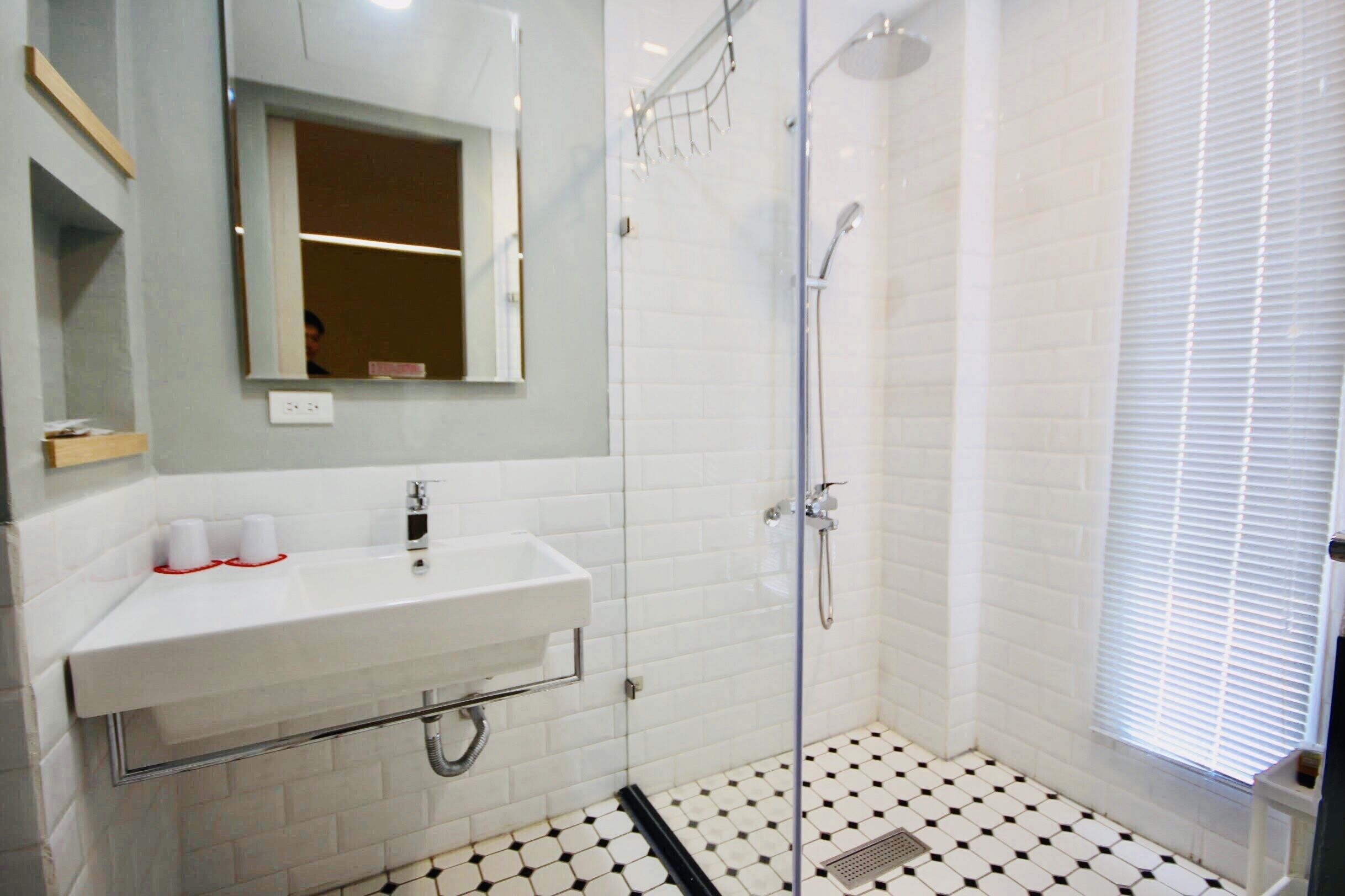 Un baño con lavamanos, espejo y ducha blancos.