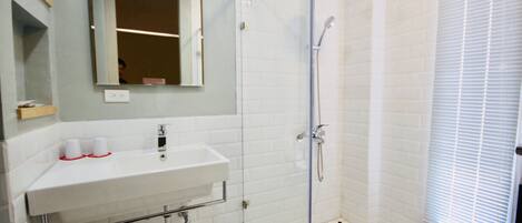 Un baño con lavamanos, espejo y ducha blancos.