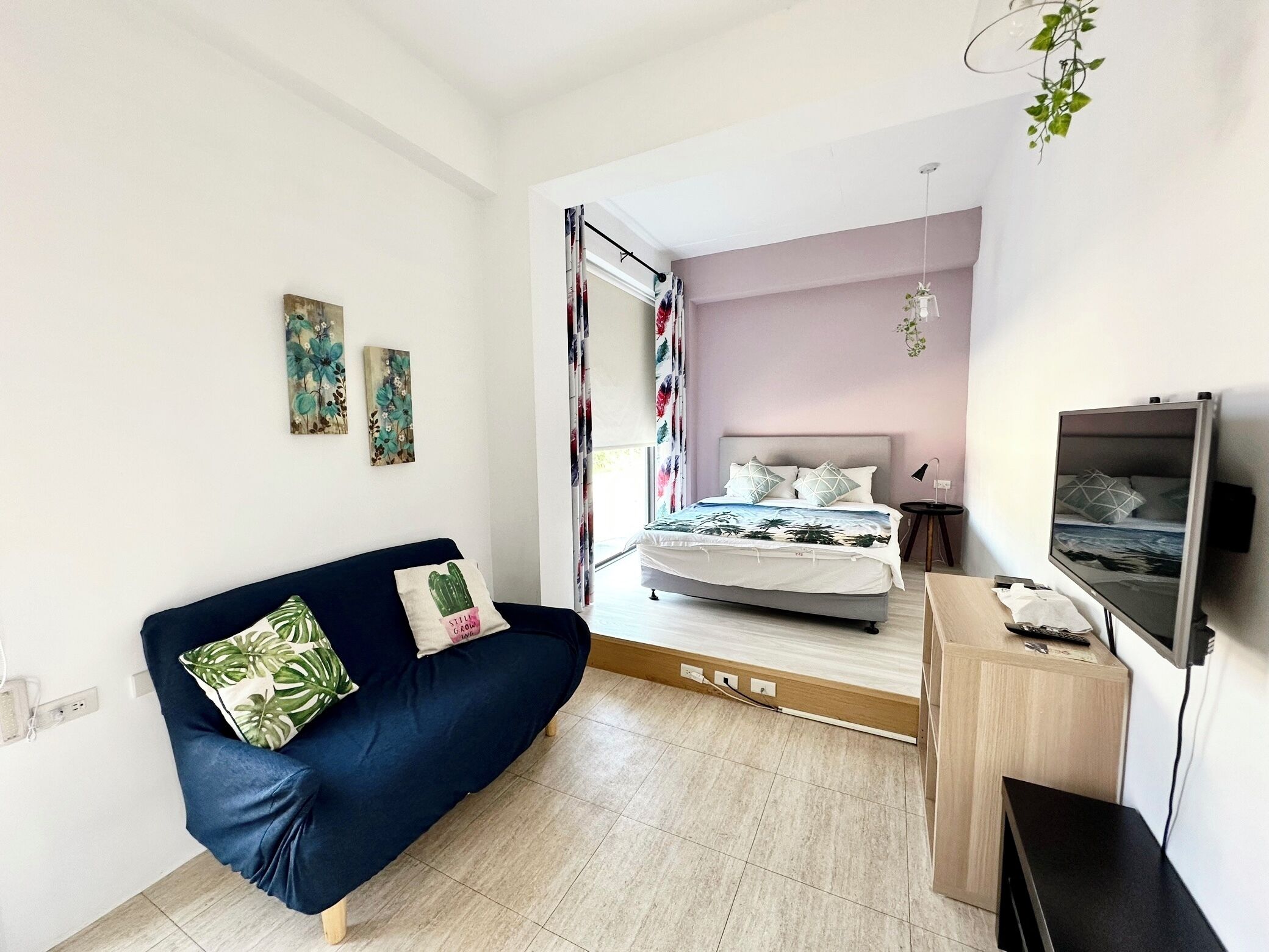 A modern bedroom with a bed, a sofa, a TV, and a desk.