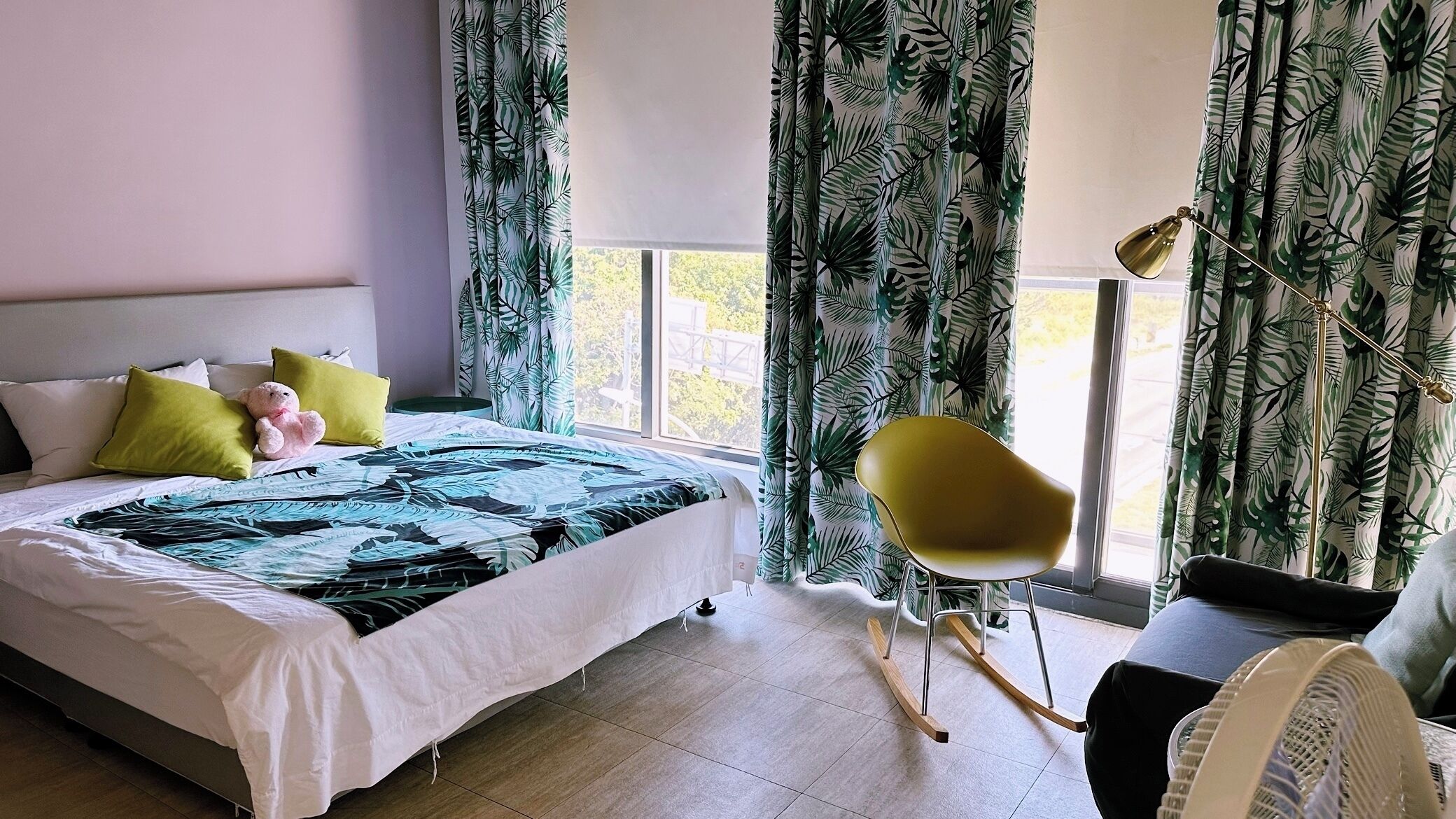 A bedroom with a bed, pillows, a chair, and curtains.
