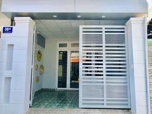 A building entrance with a gated door, a sign indicating the address, and a tiled floor.