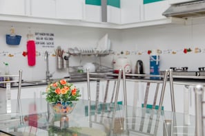 Une cuisine moderne avec des meubles blancs, une table à manger en verre et un vase décoratif rempli de fleurs.