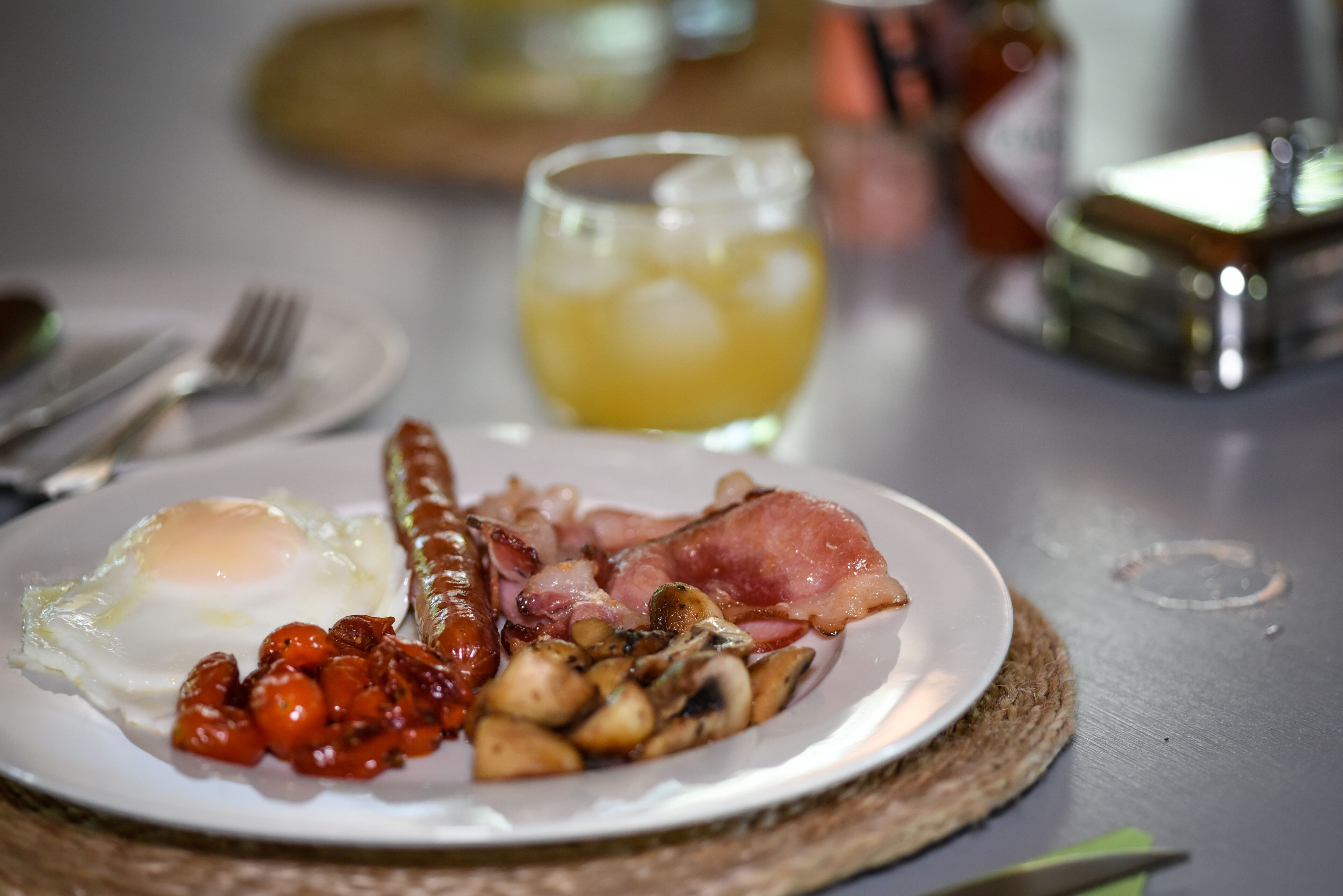Un plato de desayuno con huevos, salchichas, tocino, champiñones y tomates.