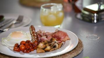 Un plato de desayuno con huevos, salchichas, tocino, champiñones y tomates.