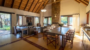 A spacious living area with a dining table, sofas, and a kitchen area. - Leopard's Lair Bush Lodge (Hoedspruit)
