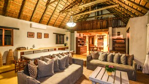 A spacious living area with a high ceiling, a dining table, sofas, and a coffee table. - Leopard's Lair Bush Lodge (Hoedspruit)