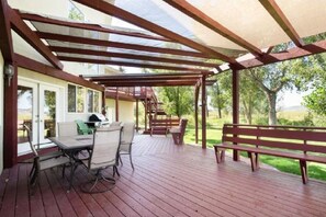 Une terrasse couverte avec une table et des chaises, un barbecue et un banc.