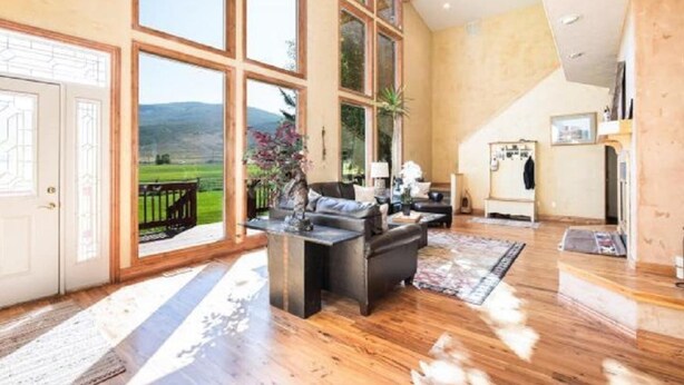 Un salón amplio con ventanas grandes, una chimenea y una zona de cocina.
