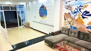 Un área de recepción con un sofá, una mesa de centro de vidrio y un mural de vida marina.