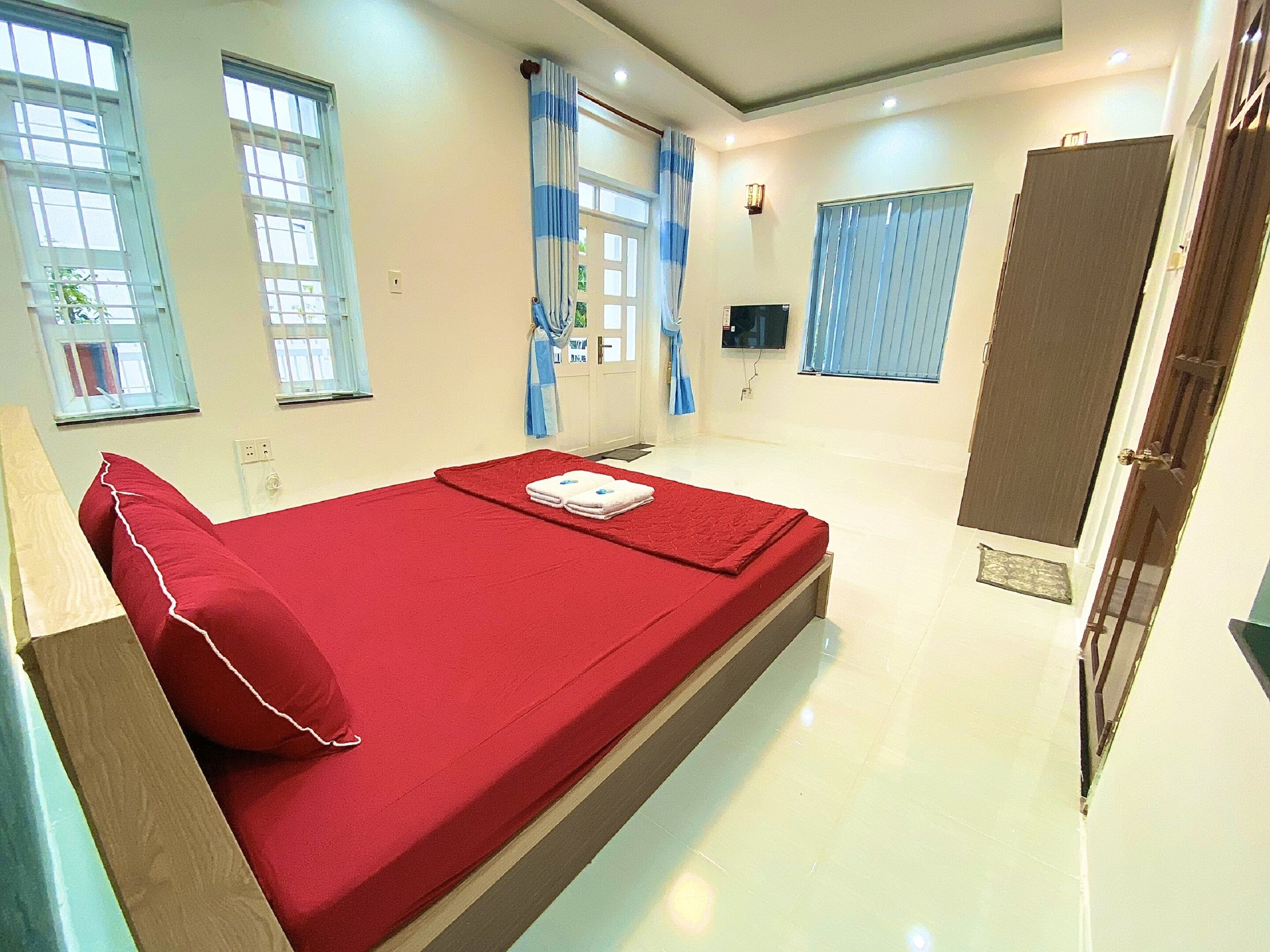 A hotel room with a single bed, a television, and a door.