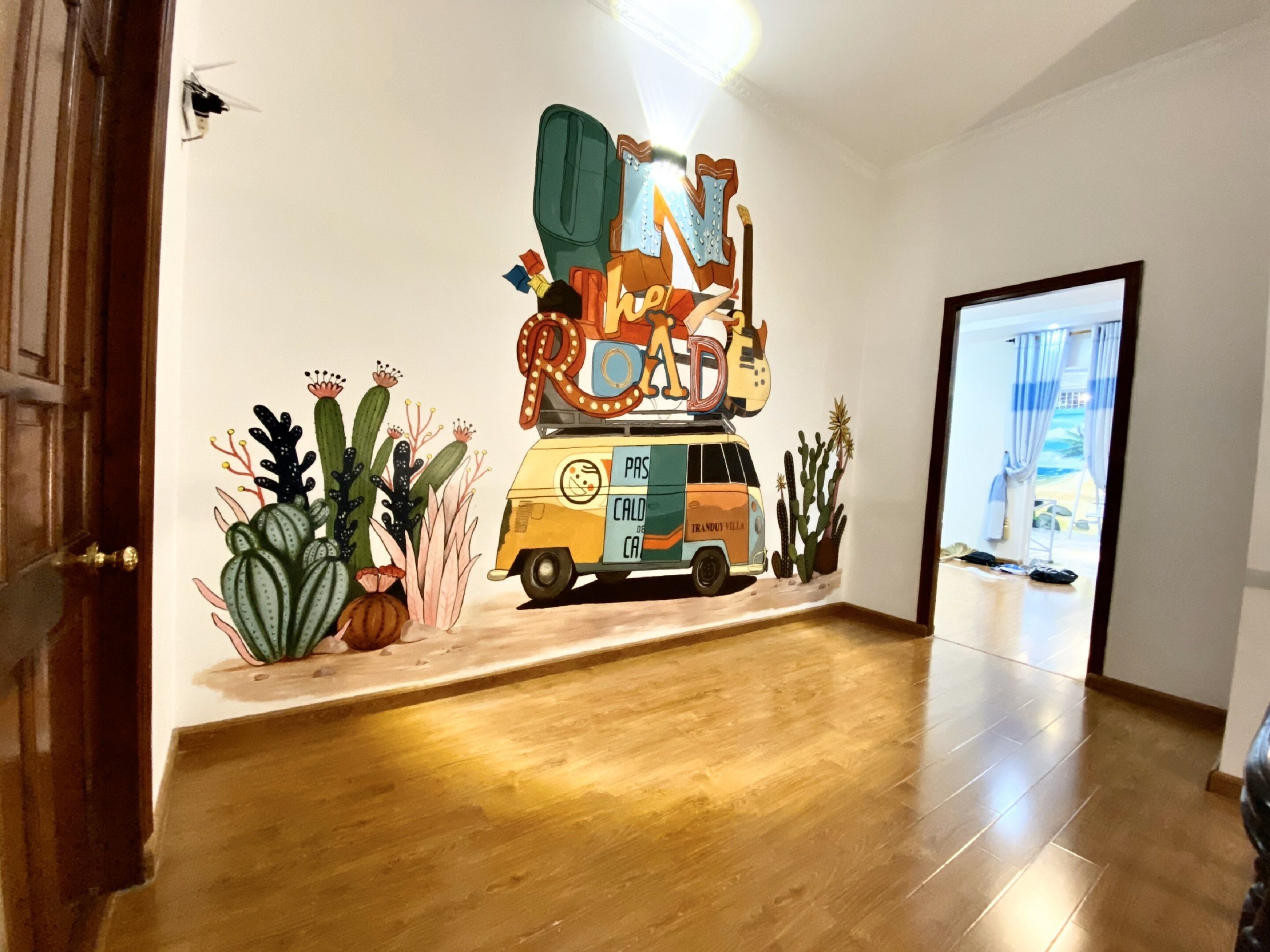 A hallway with a wall mural of a vintage van and desert plants.