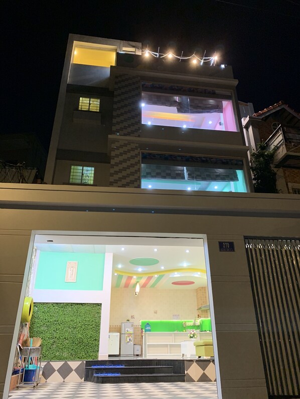 Un hôtel à plusieurs étages au design moderne, doté d’un hall d’accueil agrémenté d’un mur végétal et d’une cuisine visible au rez-de-chaussée.